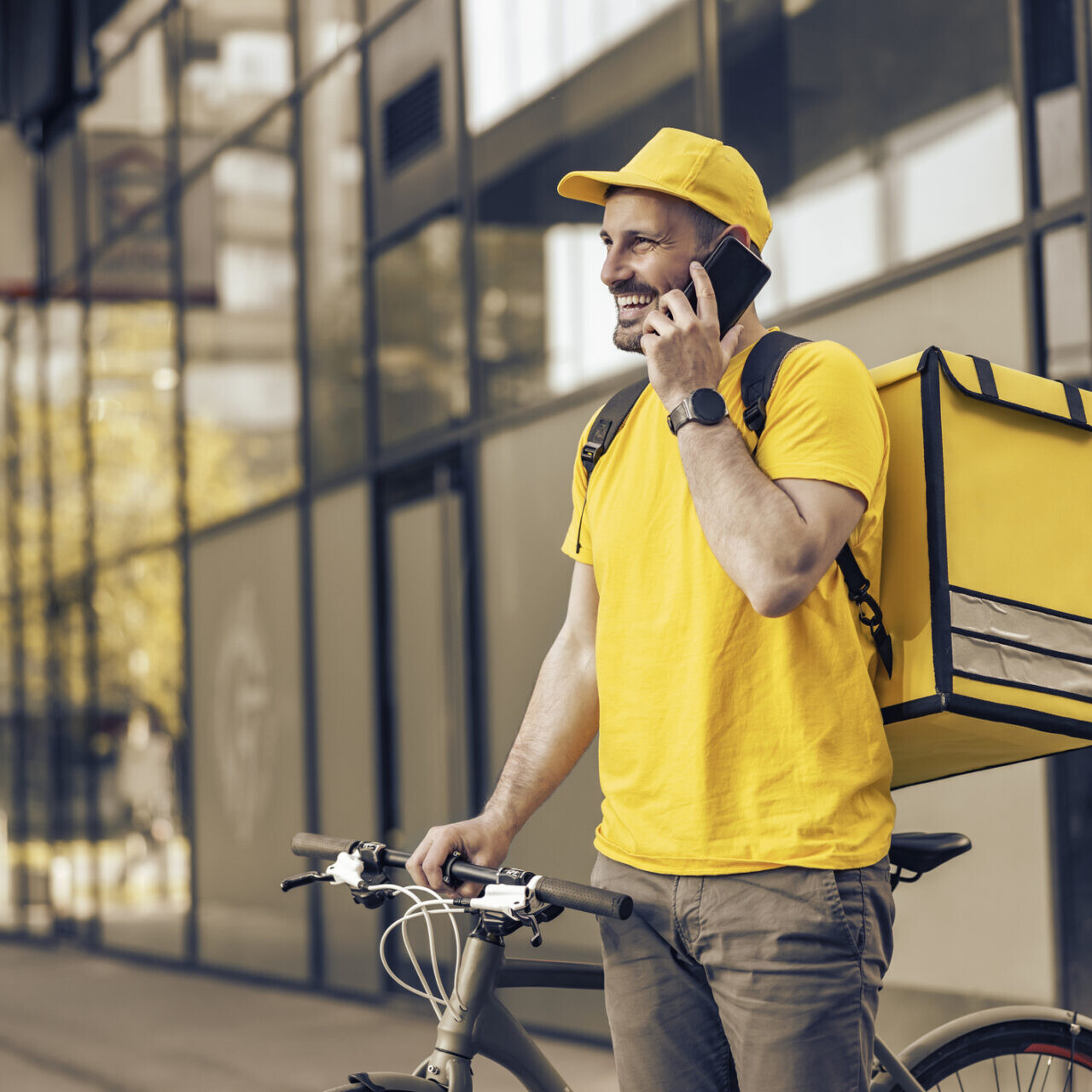 Homme faisant un petit boulot de livraison pour augmenter ses revenus, avec un vélo et un sac jaune en ville.