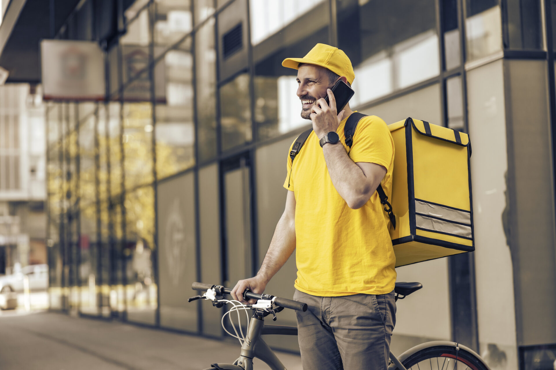 Homme faisant un petit boulot de livraison pour augmenter ses revenus, avec un vélo et un sac jaune en ville.