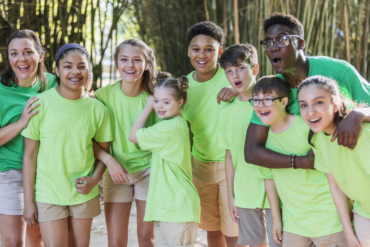 Un groupe d’enfants souriants participe à un camp d’été, profitant d’activités de plein air amusantes en équipe.