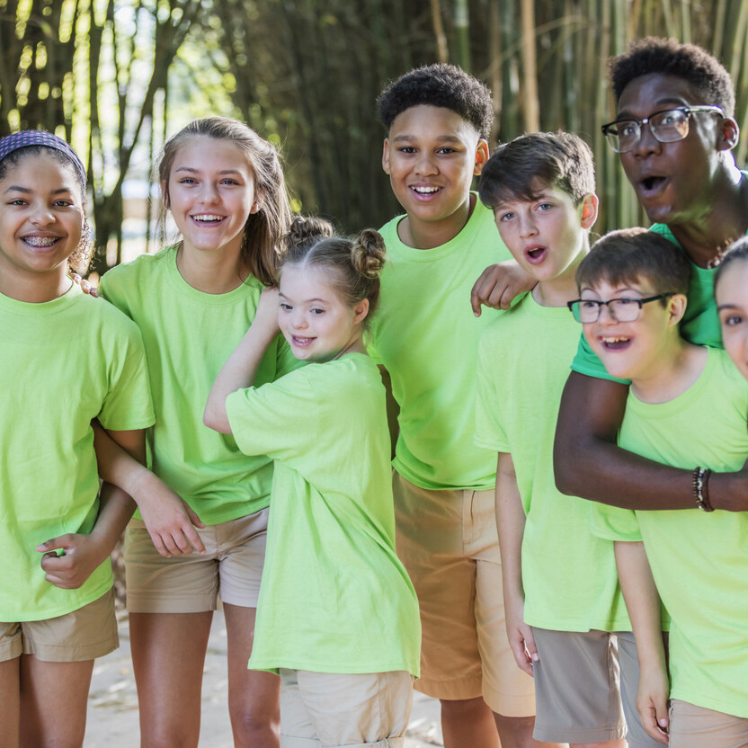 Un groupe d’enfants souriants participe à un camp d’été, profitant d’activités de plein air amusantes en équipe.