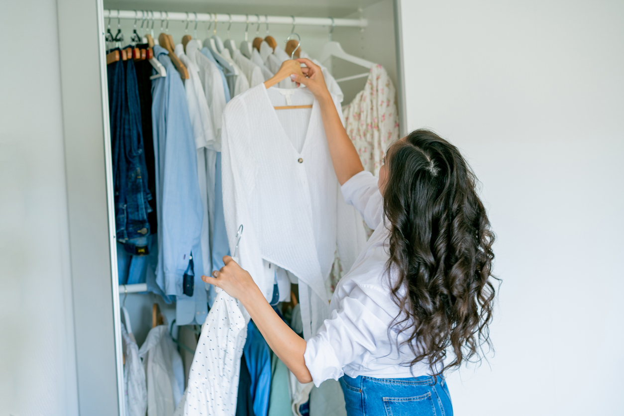 Femme triant sa garde-robe pour créer un style chic pas cher avec ses vêtements existants.