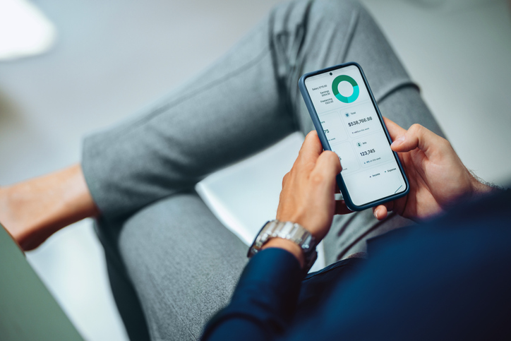 Personne utilisant une application de budget sur son téléphone intelligent pour gérer ses finances personnelles.