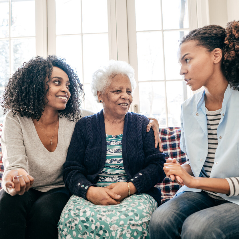 Soins à domicile : une infirmière et une proche aident une mère âgée, montrant l’importance de s’occuper de ses parents âgés.