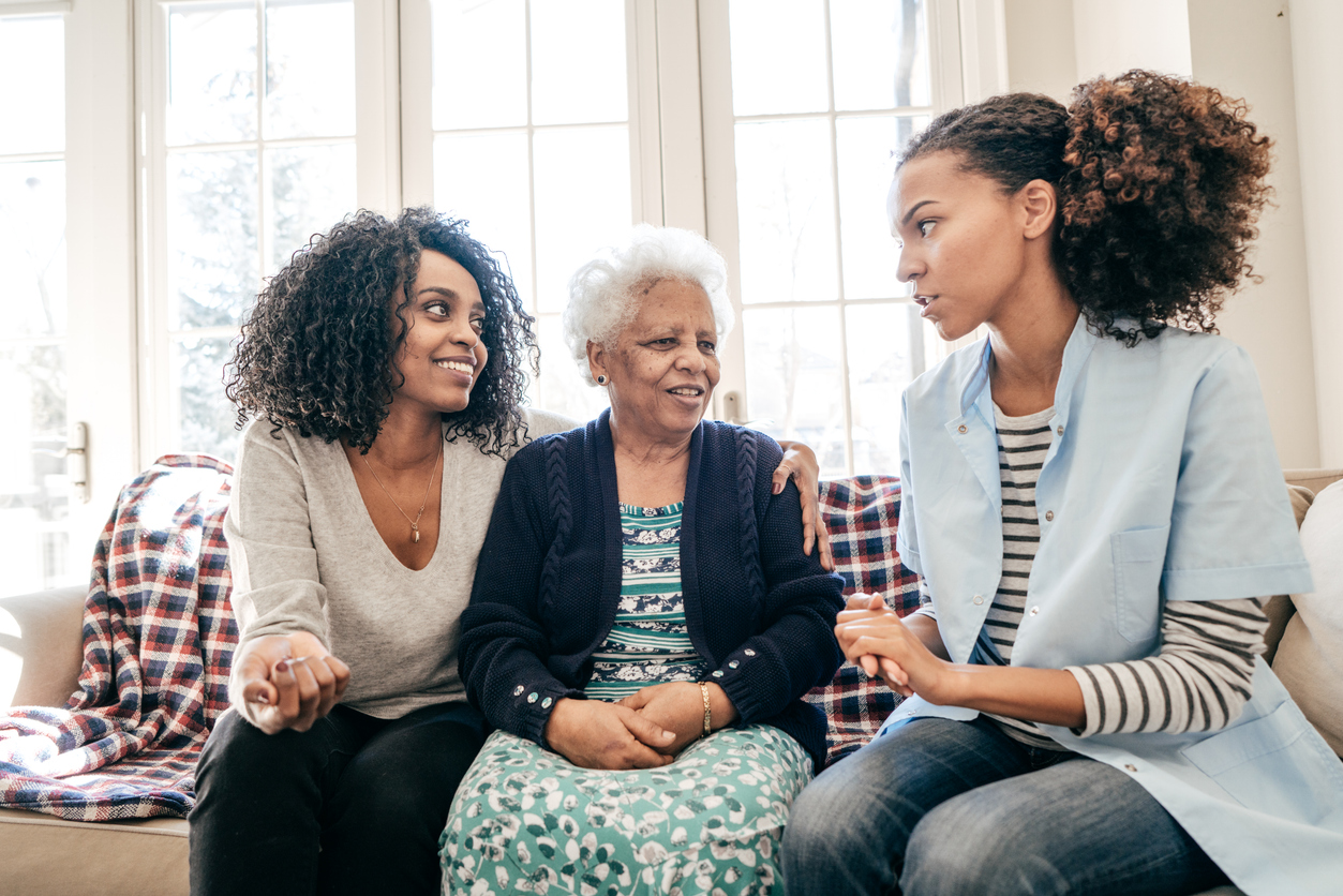 Soins à domicile : une infirmière et une proche aident une mère âgée, montrant l’importance de s’occuper de ses parents âgés.