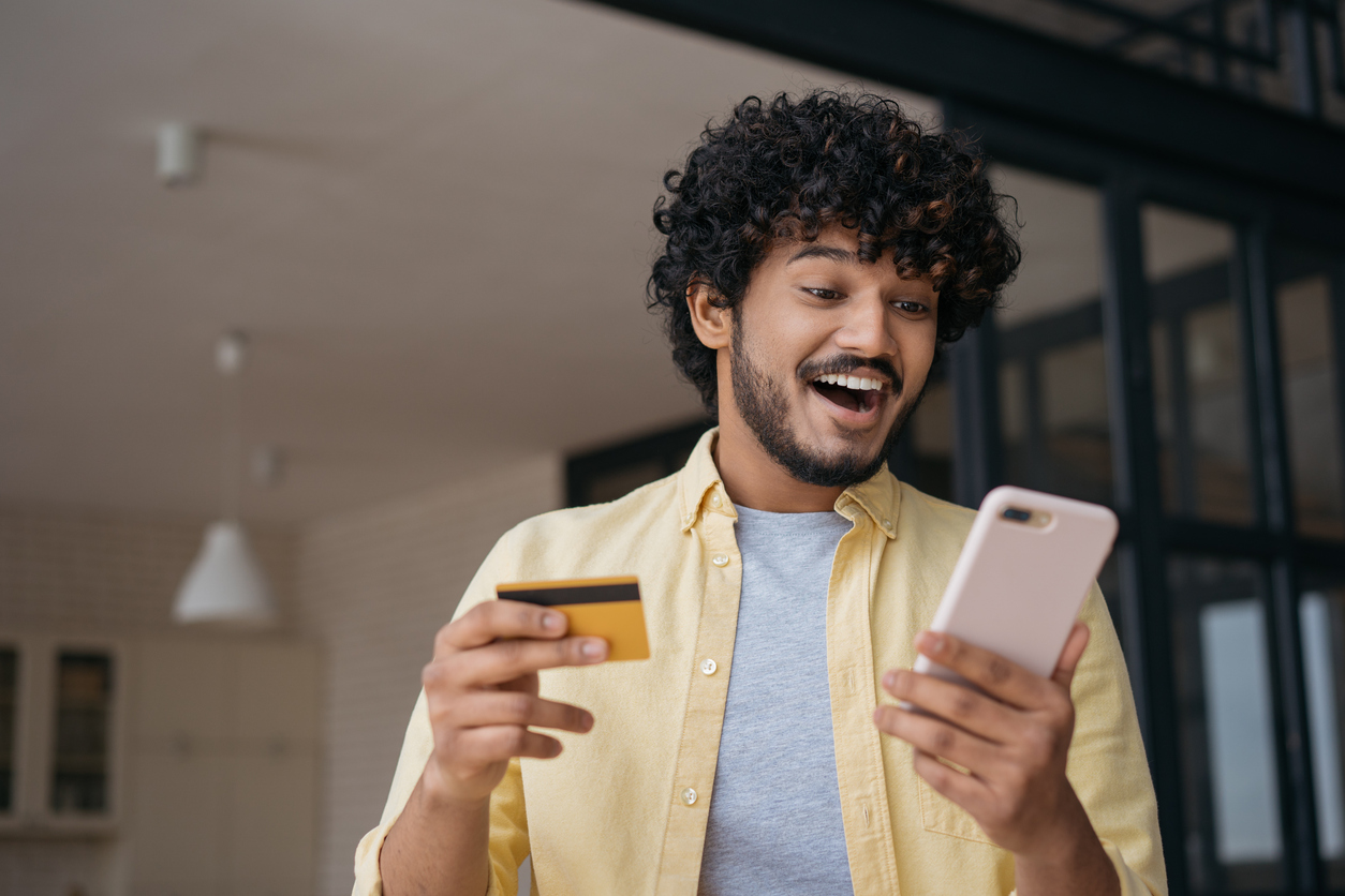 Jeune adulte découvrant des avantages grâce à sa carte de crédit à récompenses sur son téléphone.