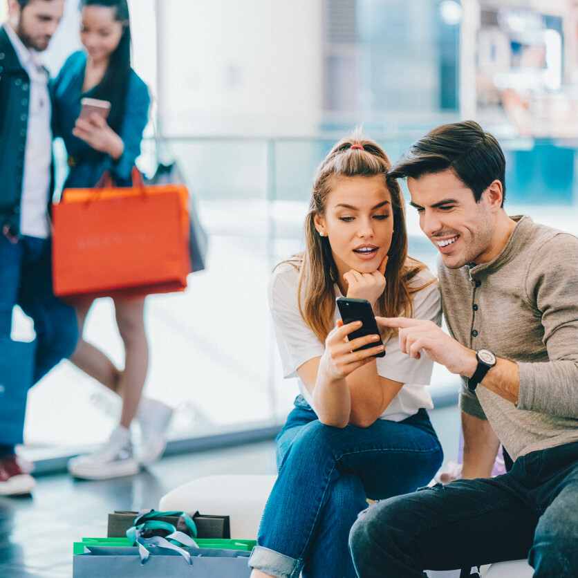 Jeunes adultes magasinant avec des amis et subissant la pression sociale qui influence leurs dépenses.