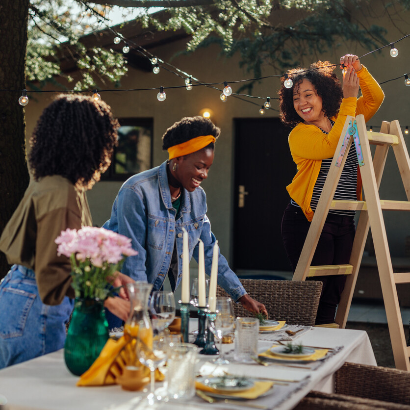 mis décorant une table extérieure avec des guirlandes lumineuses pour un budget évènement convivial.